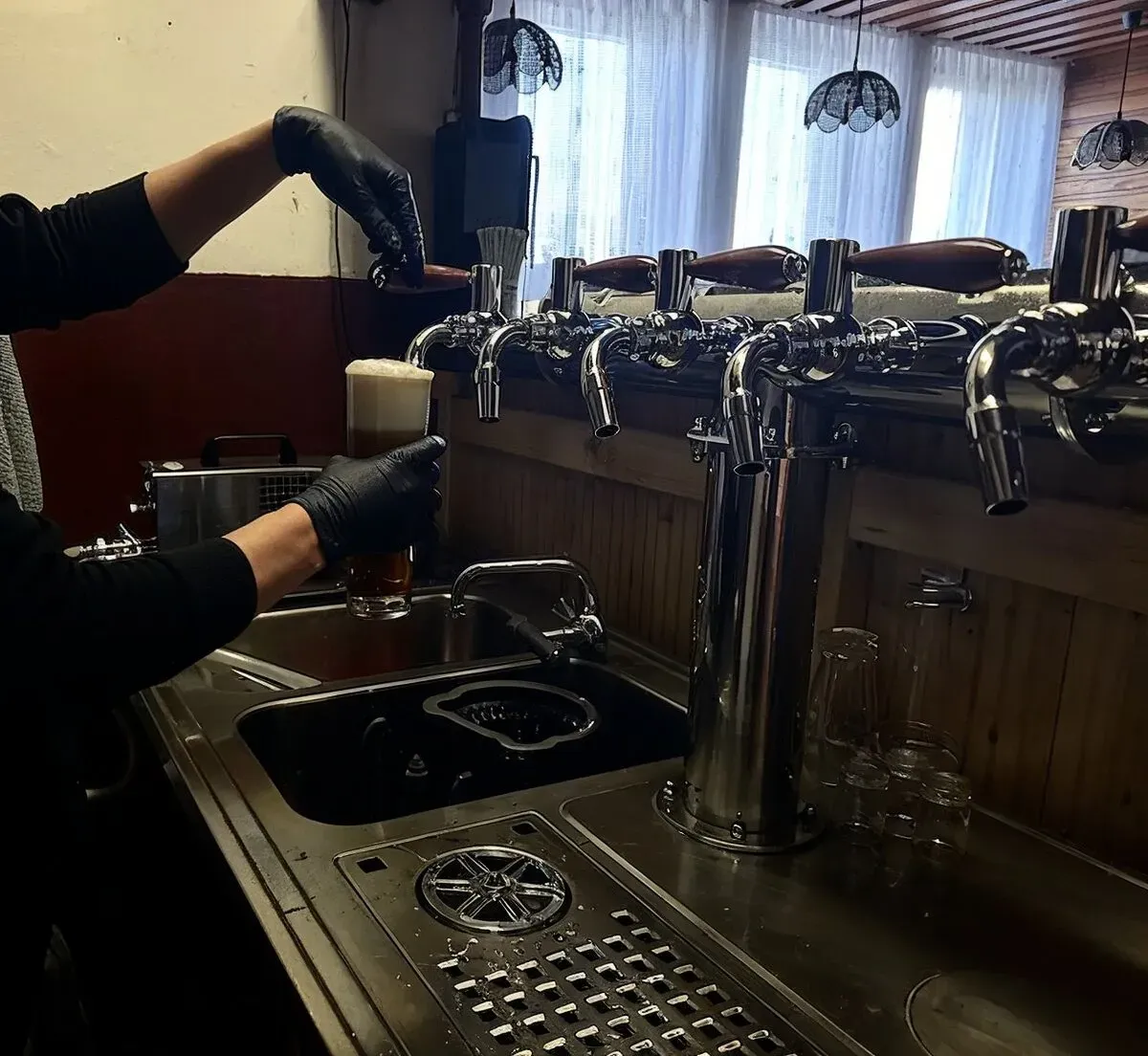 Odborník v černých rukavicích provádí čištění a sanitaci pivního vedení pro zajištění perfektní kvality piva